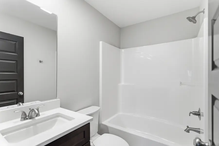 Bathroom with a tub shower and dark vanity