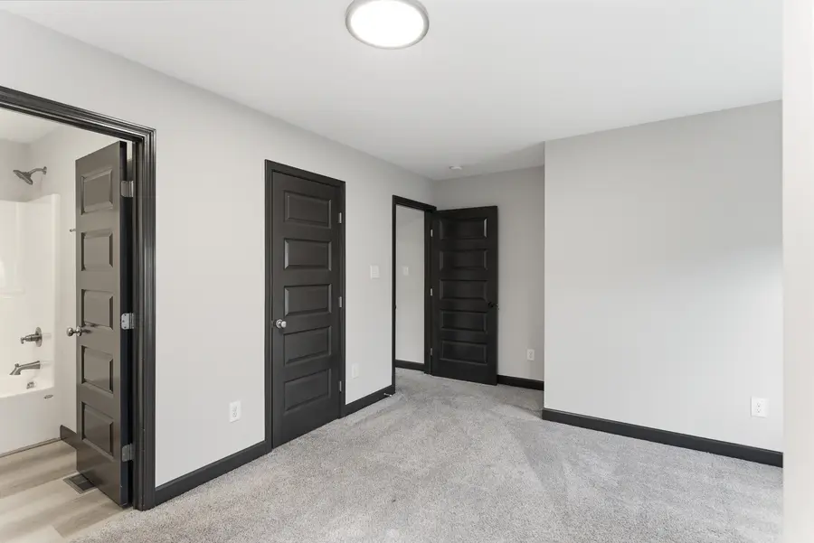Carpeted bedroom with doors to the bath and hall