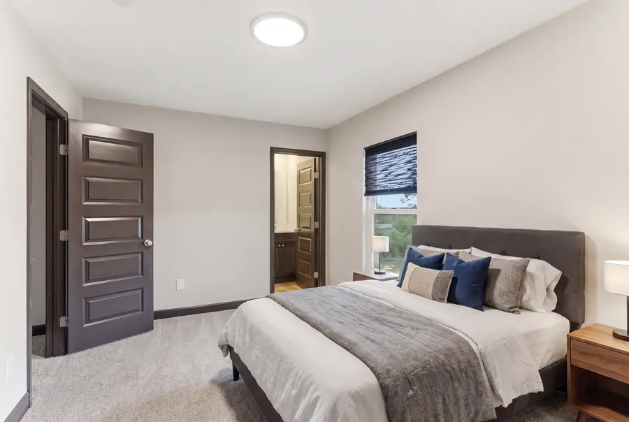 Staged carpeted bedroom with a bed and nightstand
