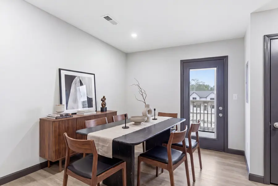Staged dining area with a wood table beside the rear door