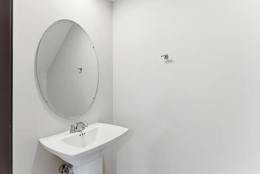 Half bath with a pedestal sink and oval mirror