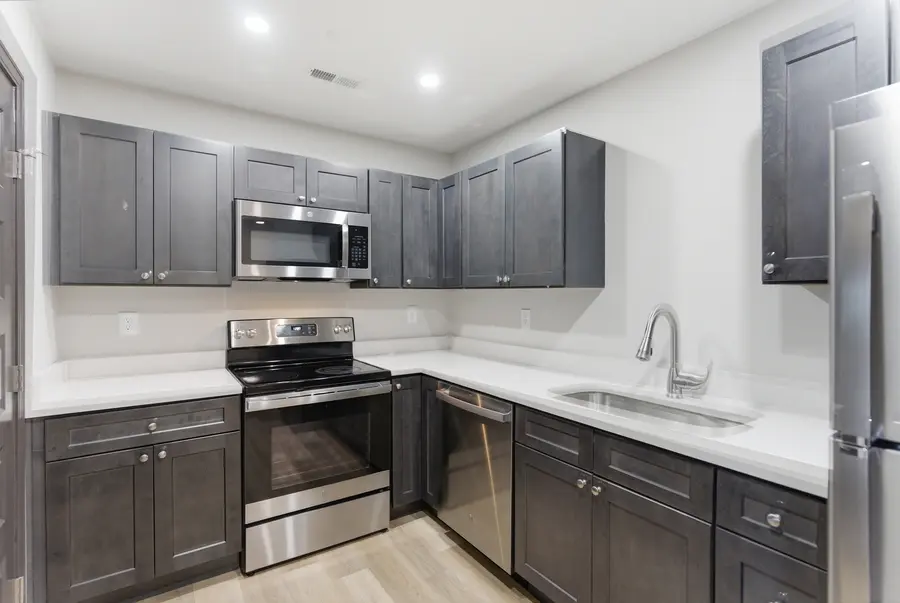 Kitchen with dark cabinets, a stainless range and white counters