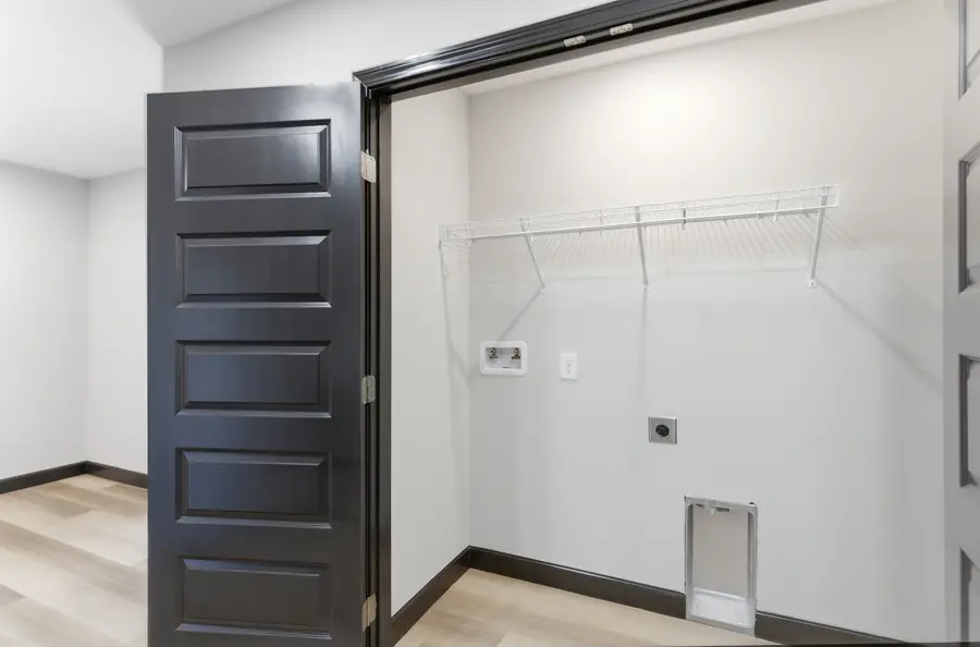 Laundry closet with washer and dryer hookups and a wire shelf