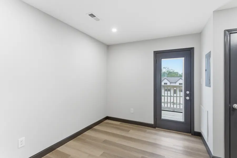 Rear entry to a townhome with a glass door and light plank floors