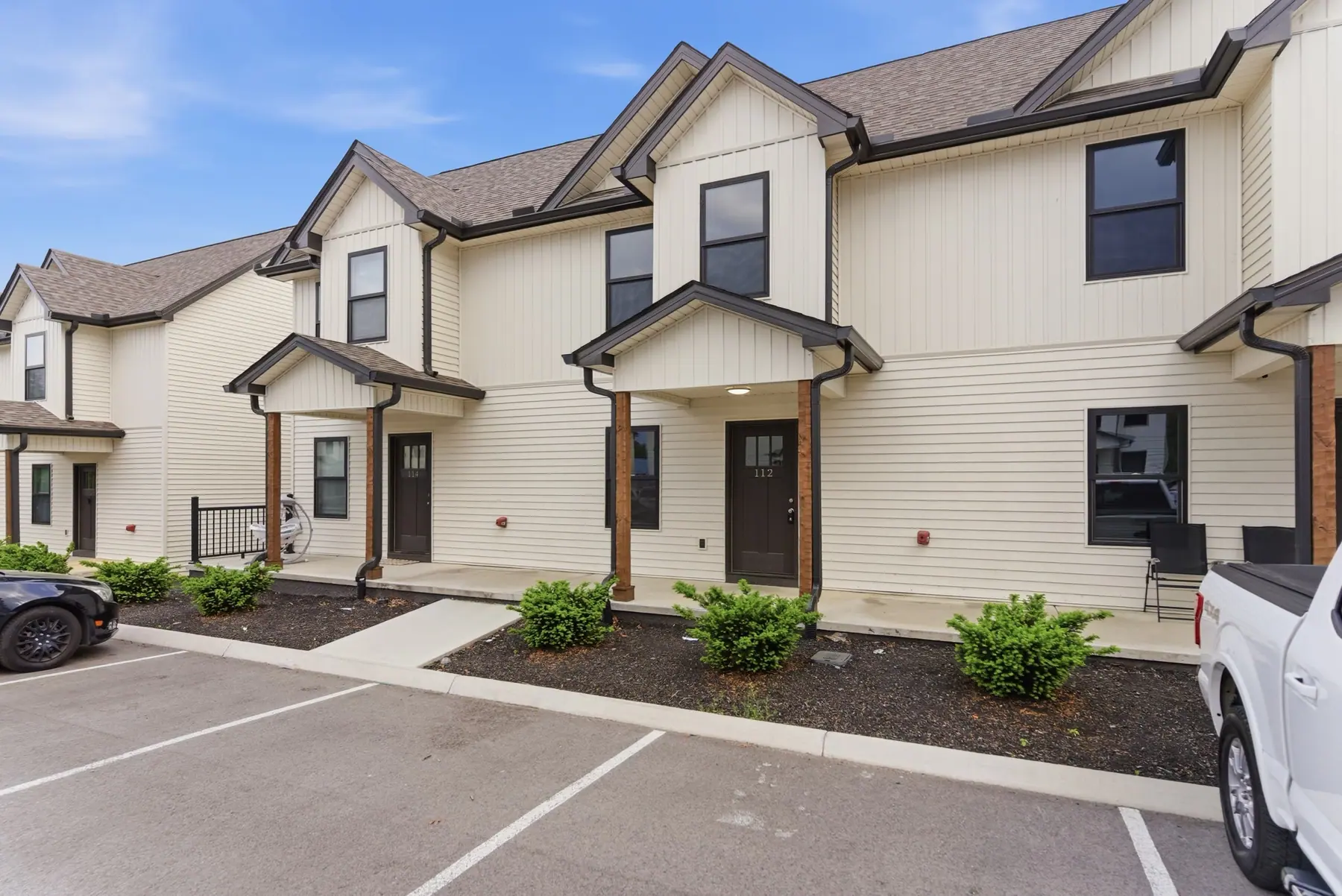 The same row of two-storey townhomes seen from an angle, with covered porches and parking along the front