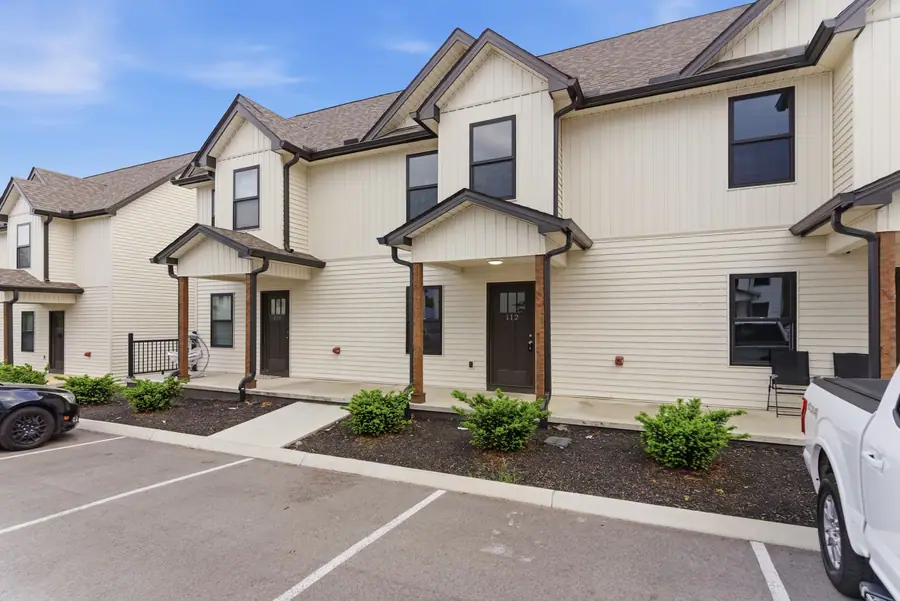 The same row of two-storey townhomes seen from an angle, with covered porches and parking along the front