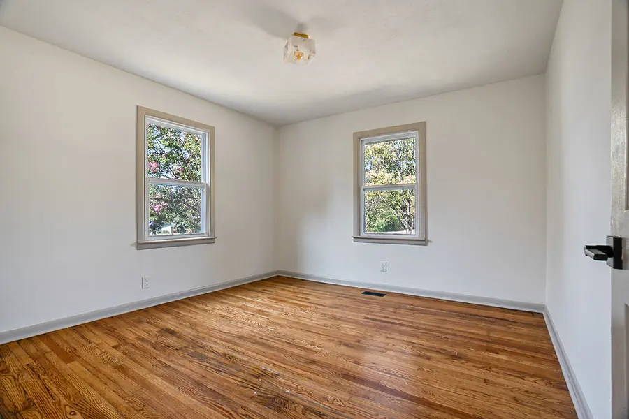 Bedroom with hardwood floors and two windows