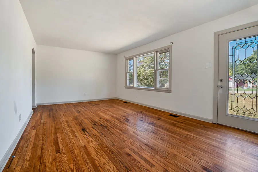 Living room with refinished hardwood floors and a glass front door