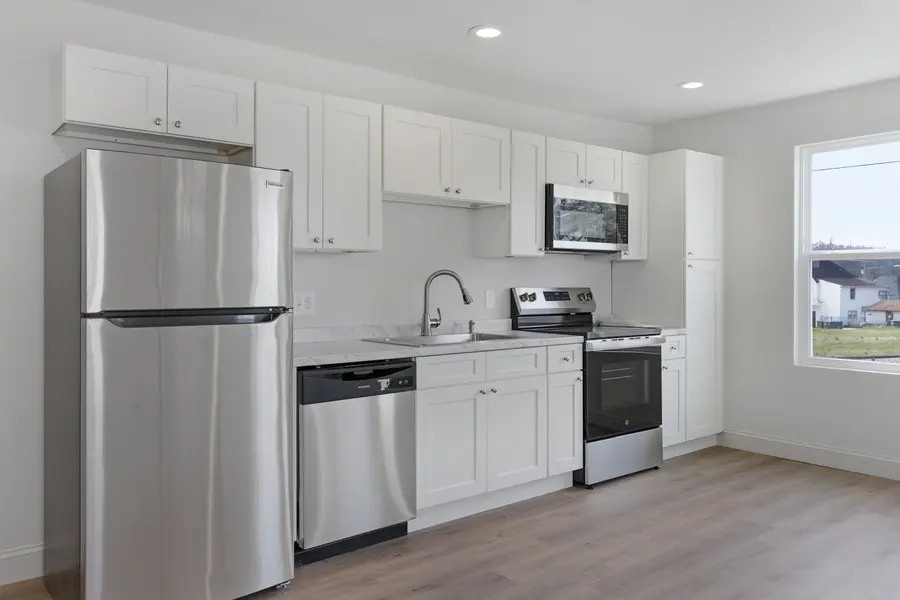 White kitchen with a stainless refrigerator and range