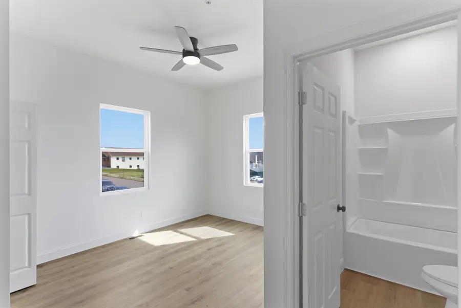 Bedroom with a ceiling fan beside the bathroom door