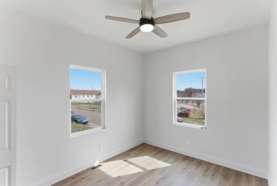 Bright bedroom with two windows and a ceiling fan