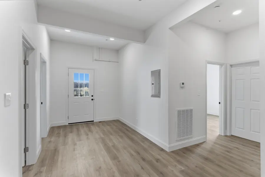 Unit living area with the front door and plank floors