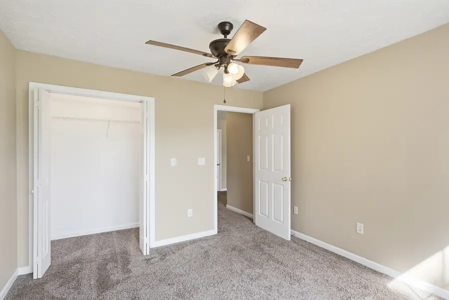 Carpeted bedroom with a double closet and ceiling fan
