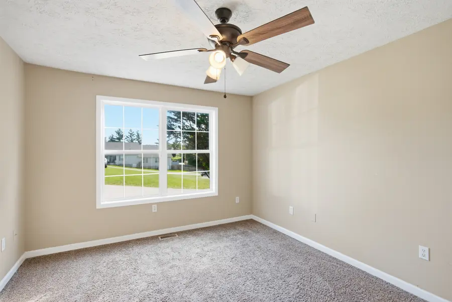 Carpeted bedroom with a large window and ceiling fan
