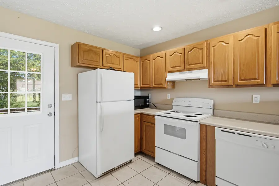 Kitchen with oak cabinets, white appliances and a side door