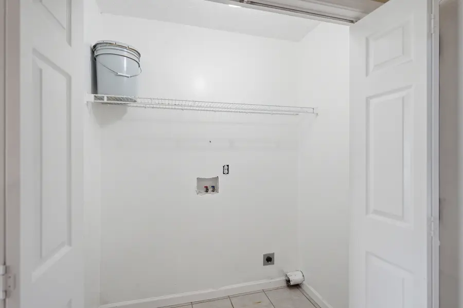 Laundry closet with hookups and a wire shelf