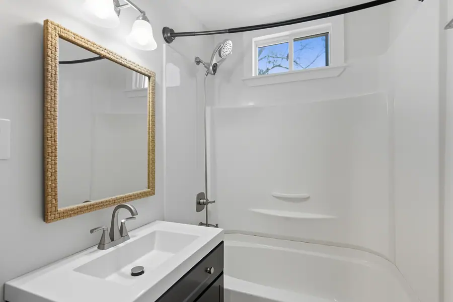 Bathroom vanity with a framed mirror and a tub shower