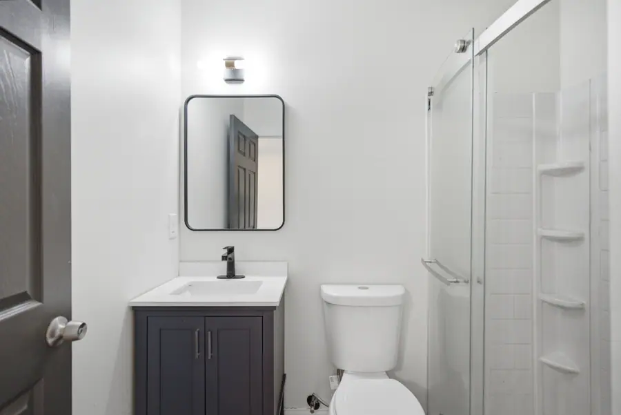 Renovated bathroom with a grey vanity and glass shower