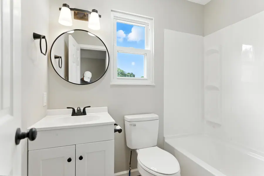 Bathroom vanity with a round mirror and modern fixtures