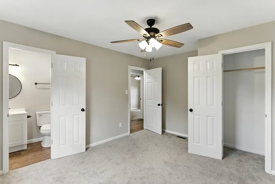 Carpeted bedroom with an adjoining bathroom and closet