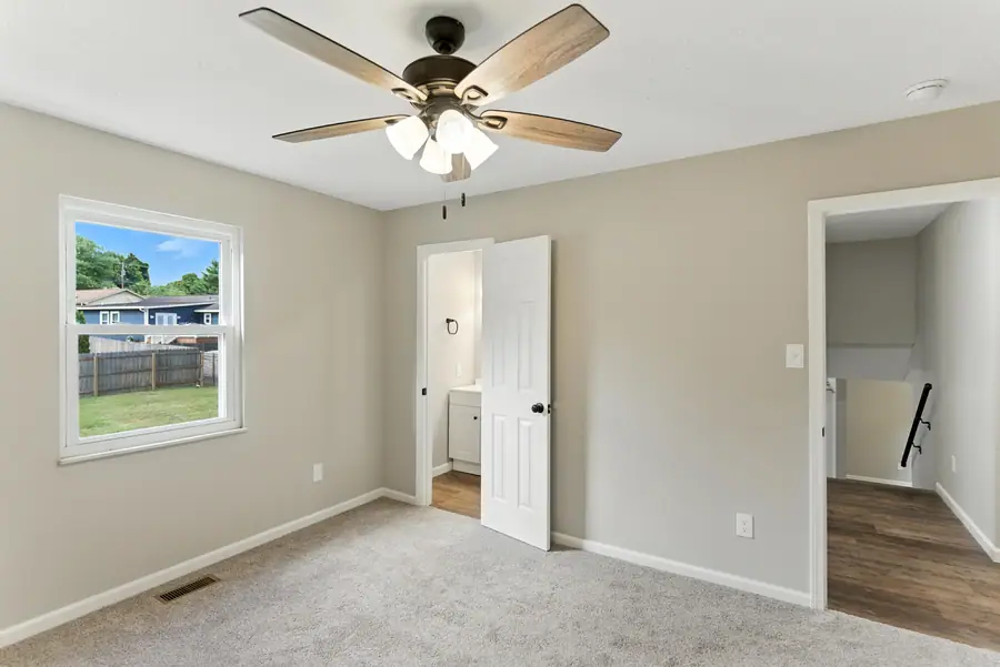 Carpeted bedroom opening to the hallway and bathroom