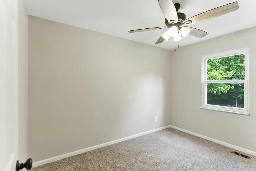 Carpeted bedroom with a ceiling fan and a window