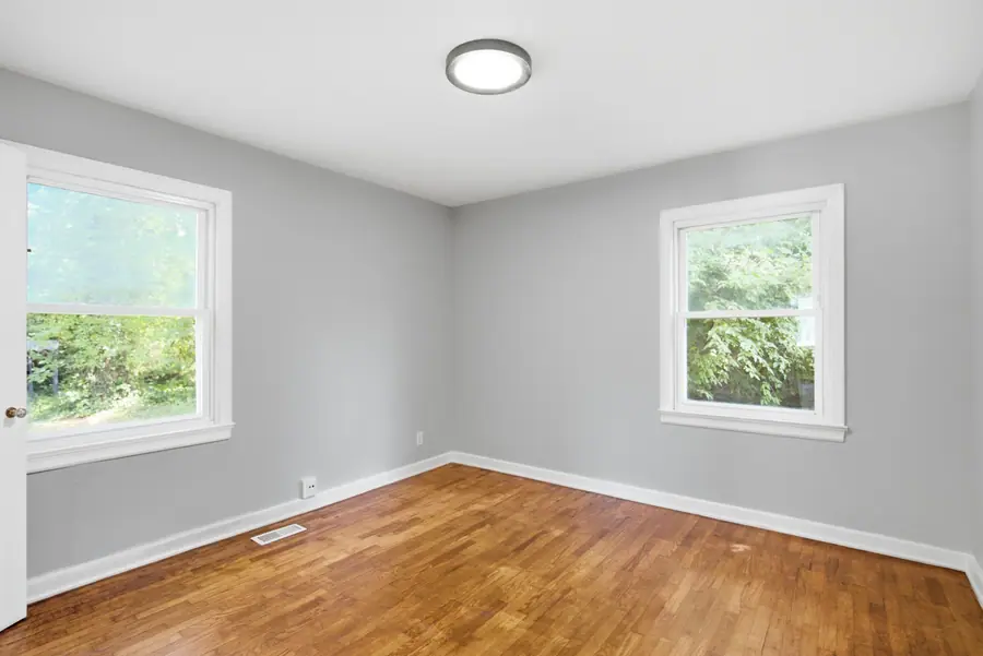 Corner bedroom with hardwood floors and painted trim