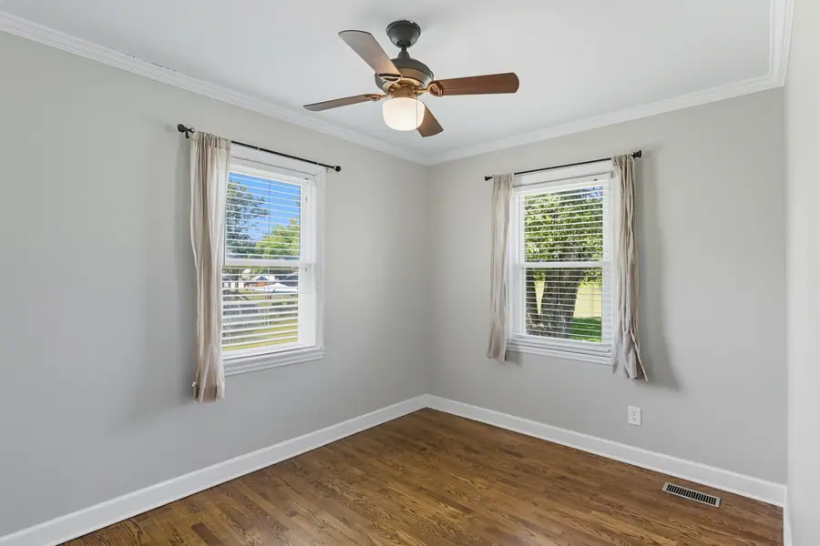 Bedroom with curtained windows and hardwood floors