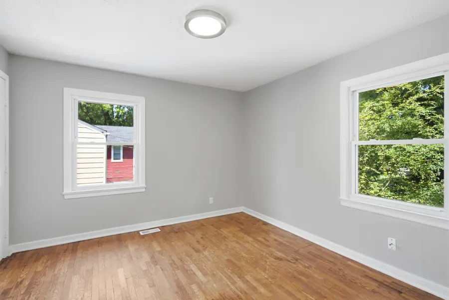 Bedroom with hardwood floors and two windows