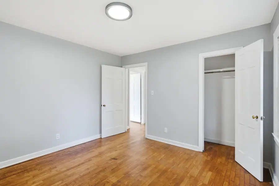 Bedroom with an open closet and refinished hardwood