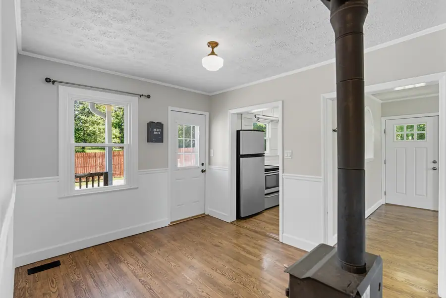 Living room with a wood stove flue and painted wainscot
