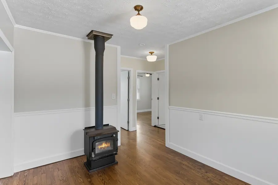 Living room with a wood burning stove and painted wainscot