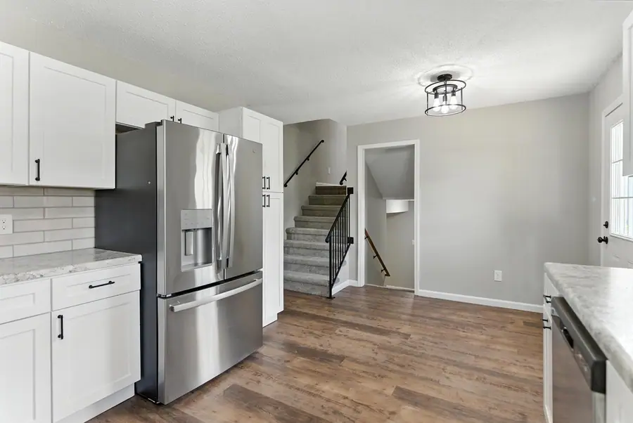 Kitchen with subway tile and stainless appliances beside the stairs