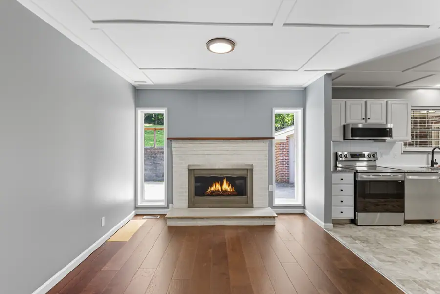 Living room with a fireplace open to the kitchen