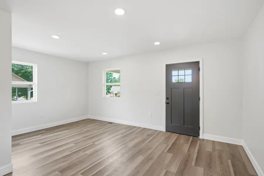 Living room with luxury vinyl plank flooring and a dark entry door